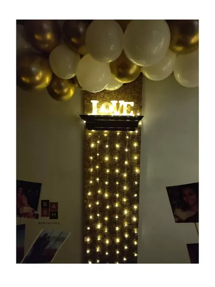 A detail shot of the fairy light wall, topped with an illuminated 'LOVE' sign. This element adds a warm, magical glow to the room and serves as a beautiful focal point for a romantic evening.