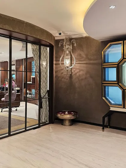 A detail shot at KR Sons highlights the layering of textures and materials. A classical wall sconce casts a warm glow on the textured walls, while a bespoke octagonal display cabinet with gold leaf detailing adds a touch of modern opulence.