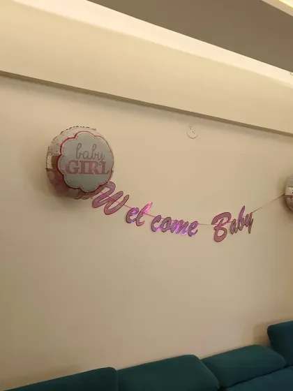 A simple "Welcome Baby" banner with "Baby Girl" foil balloons on the wall, perfect for a subtle and sweet home celebration.