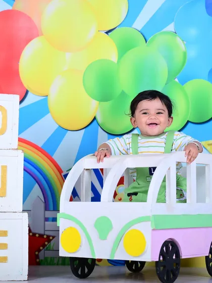 A Cocomelon-themed first birthday shoot, with the baby in a colorful bus prop.