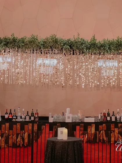 A well-styled bar is crucial for any celebration. For this Sangeet, I designed a chic bar with a crystal curtain backdrop and dramatic overhead greenery, blending glamour with natural elements.