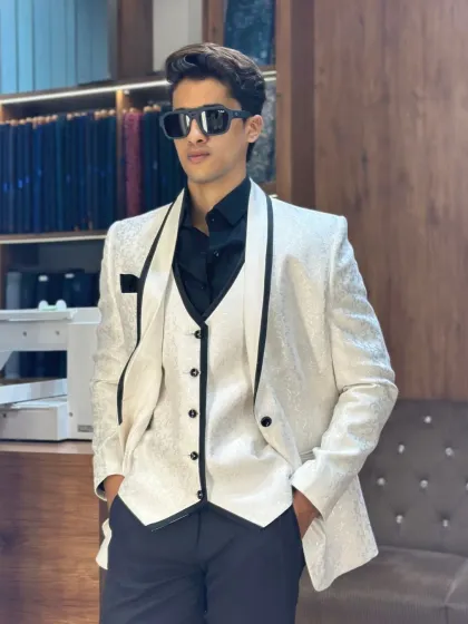 For the man who wants to own the room. A sharp white three-piece tuxedo with a contrasting black waistcoat and lapels, tailored for a flawless, modern silhouette.