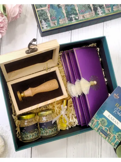 A luxurious Rakhi hamper for a brother, featuring a custom wax seal stamp, gourmet goodies, and elegant purple envelopes.