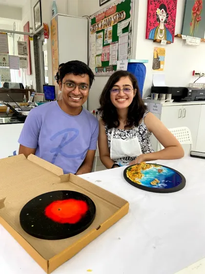 A couple with their finished resin art, one a galaxy clock and the other a beach scene. My workshops are perfect for couples looking for a creative date.