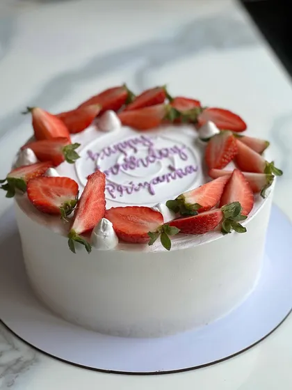 A simple and elegant strawberry cream cake. The clean white frosting provides the perfect canvas for the fresh, bright red strawberries on top.