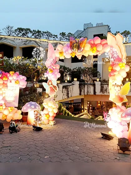 A wide shot of the enchanting outdoor entrance for the fairy and butterfly party. The setup includes two balloon arches and illuminated props, creating a grand and magical welcome.