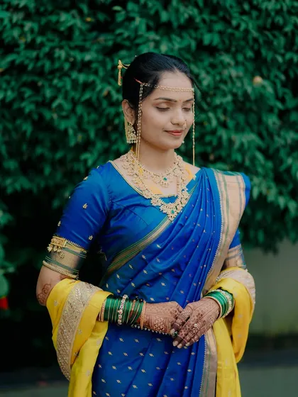 A serene and beautiful portrait of the bride against a lush green background, her traditional attire and jewelry perfectly captured.
