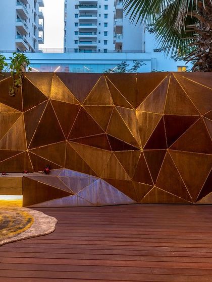 A wall art piece inspired by origami, with embedded lighting that highlights its geometric folds. This custom installation transforms a simple compound wall into a captivating centerpiece, especially at night.