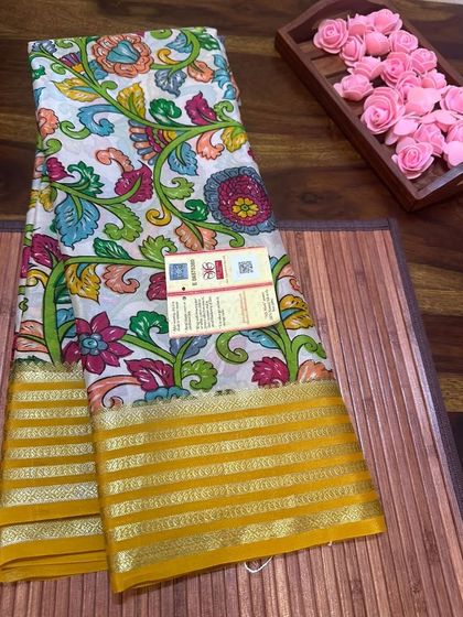 A colorful floral Kalamkari print on a white Mysore silk saree with a yellow border.