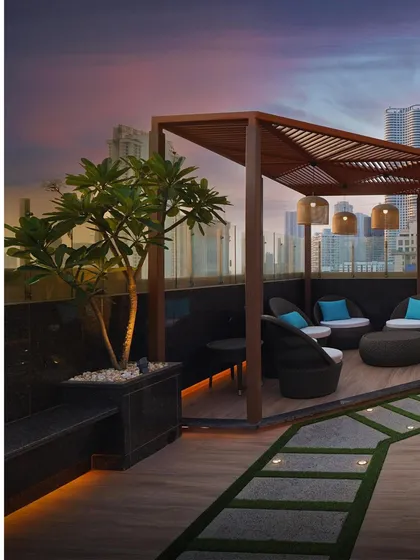 Another view of the rooftop terrace in Lower Parel. The combination of wood decking, comfortable seating, and greenery creates a warm and inviting atmosphere against the urban backdrop.