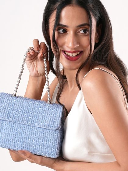 A model smiles while holding the powder blue version of my crystal bag. The silver chain strap perfectly complements the cool tone of the intricate beadwork, making it a chic party accessory.