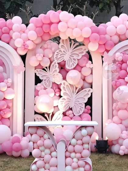 A full view of the outdoor pink butterfly installation. This photo shows how the different elements, including arches and a butterfly-shaped table, come together to create a cohesive and breathtaking party environment.