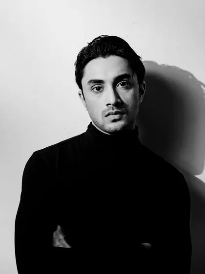 A strong, direct portrait. The high contrast lighting and the simple black turtleneck focus all the attention on the subject's expression, making it a powerful headshot.