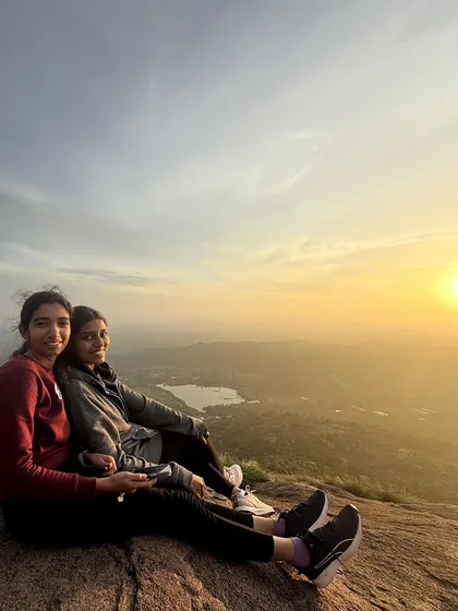 Two friends sitting together, enjoying the spectacular sunrise from the peak of Uttari Betta.