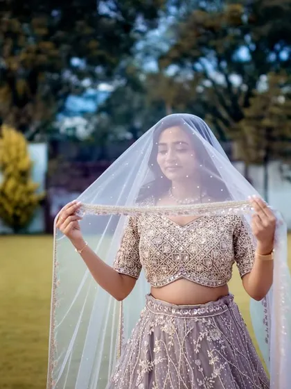 A lovely portrait of the bride-to-be holding her veil, smiling softly. This classic pose highlights her grace and happiness.