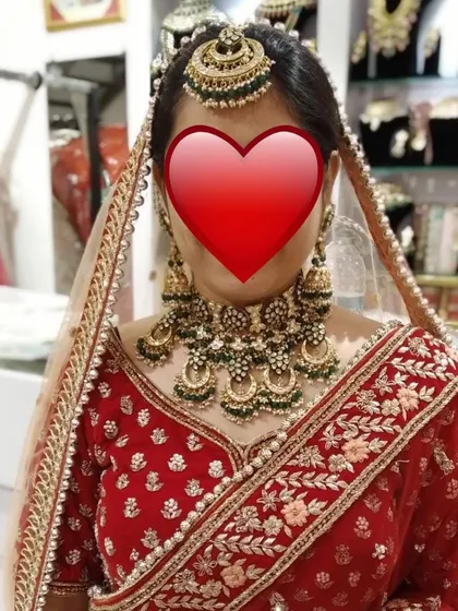 A client trying on one of our heavy bridal sets in-store. This green-beaded Kundan and pearl set is a classic choice that complements traditional red lehengas perfectly.