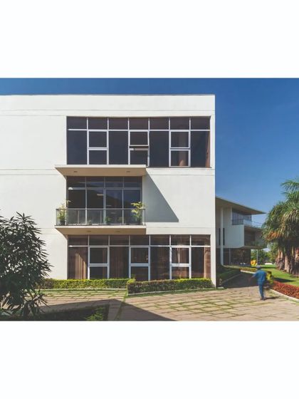 The main office block, featuring a multi-level facade with deep-set windows and balconies. This design responds to the climate by providing shade and creates a formal yet inviting presence as part of the campus master plan.