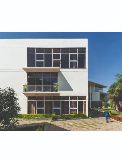 The main office block, featuring a multi-level facade with deep-set windows and balconies. This design responds to the climate by providing shade and creates a formal yet inviting presence as part of the campus master plan.