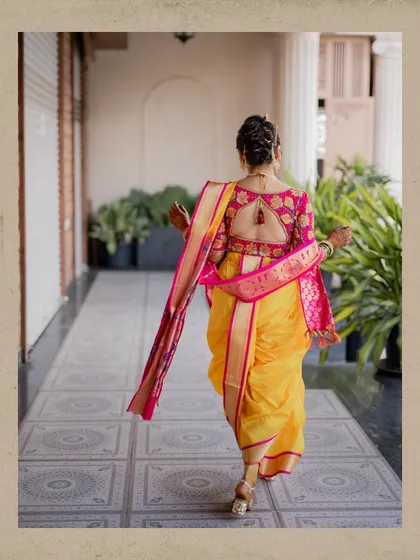 A stunning back shot of the bride in her yellow and pink nauvari saree, showing the intricate design of her blouse and her graceful posture.