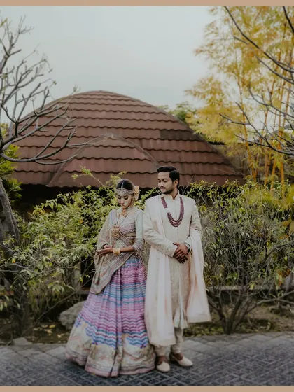 A sweet moment between the couple, framed by the unique architecture of The Ananta Udaipur. The bride's colorful lehenga adds a beautiful pop of color to the scene.