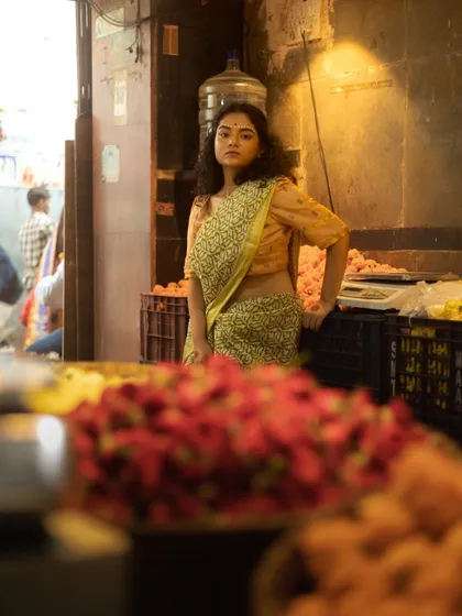 This shot places the model in a flower market, with the soft, natural makeup and curly hair creating a beautiful contrast with the rustic environment.