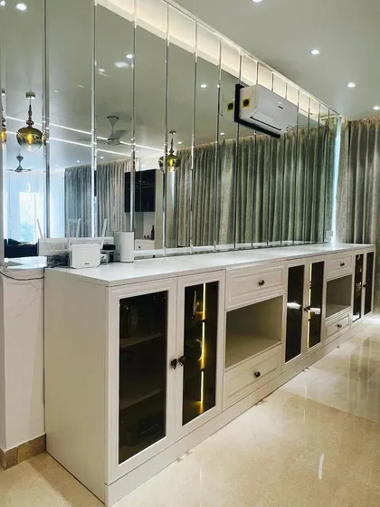 In this dining area, I used a full wall of beveled mirror panels to dramatically expand the space and reflect light. This feature acts as a glamorous backdrop for the custom white console table.