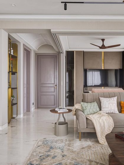 A detail shot from the 'Urban Tranquility' project, showing the layering of textures and materials. The soft grey sofa is complemented by a mix of cushions and a sleek side table.