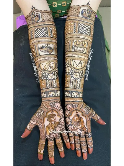 A full view of a story-based bridal mehndi. The design includes couple portraits, initials, wedding symbols, and elephants, creating a rich narrative on the arms.