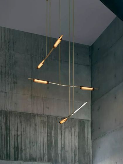The Volant system installed in a corner, its angled brass bars creating a dynamic, sculptural intervention in the architectural space.