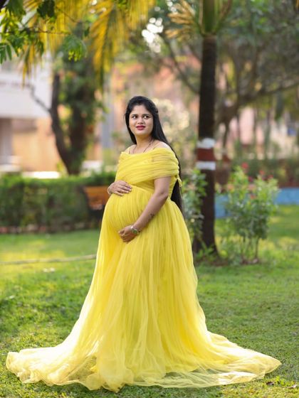 This yellow off-shoulder tulle gown flows beautifully, creating a classic A-line silhouette that is both comfortable and elegant for any maternity photoshoot.