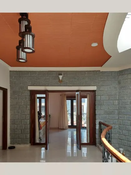 An upper-floor hallway with a stone wall and a curved ceiling detail, leading to a room with large wooden doors.