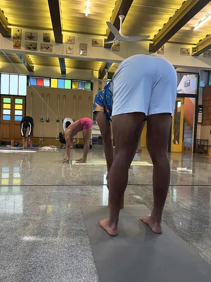 A view of athletes in Uttanasana (Standing Forward Bend). Even in a seemingly simple pose, we focus on the foundation, ensuring the legs are active and the spine is lengthening, which is critical for hamstring health and preventing lower back strain.