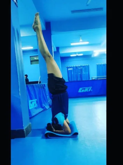 Incorporating yoga into our training helps with balance and focus. An athlete performs a supported headstand, a pose that builds upper body strength and improves circulation.