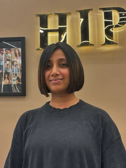A happy client showing off her new bob. The cut is perfectly symmetrical and styled sleek and straight for a polished look.
