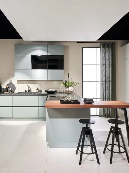 This kitchen from our 2025 novelties collection features a soft, dusty blue-green finish, paired with a wood-topped island and a built-in wine rack.
