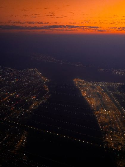 An aerial view of Prayagraj at dusk, with the city lights beginning to twinkle in anticipation of the Mahakumbh Mela. This shot captures the vastness of the sacred landscape.