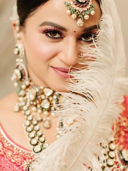 A creative close-up portrait of the bride, with a white feather gently obscuring part of her face, adding a touch of softness and mystery.