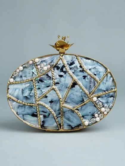 I love the mosaic-like pattern on this oval clutch, crafted with pieces of marbled blue stone and framed with delicate brass lines. Small pearls and crystals are scattered across the surface for a subtle sparkle.
