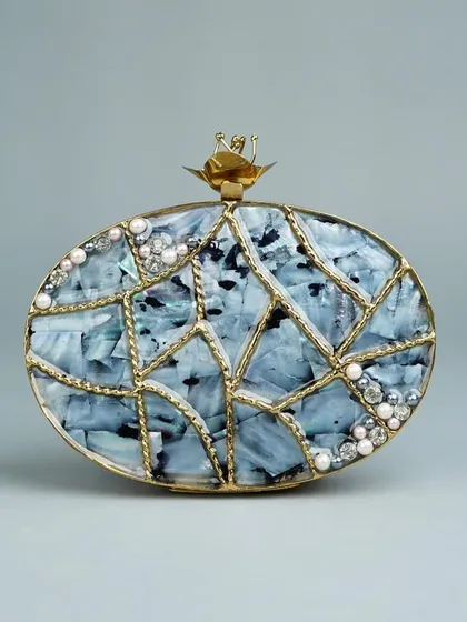 I love the mosaic-like pattern on this oval clutch, crafted with pieces of marbled blue stone and framed with delicate brass lines. Small pearls and crystals are scattered across the surface for a subtle sparkle.