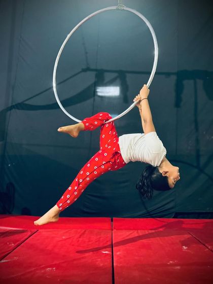A graceful pose on the bottom of the hoop, this move requires balance and core strength to hold the body in a clean, extended line.