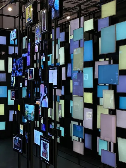 The 'Artify' installation features a wall of shifting, colored light panels, creating a dynamic and immersive soundscape. This element explores the sensory possibilities of the metaverse and the digital consumption of art.
