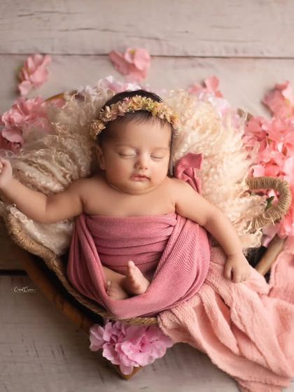 This little princess is resting in a heart-shaped prop, surrounded by soft pink flowers. The composition and colors are perfect for a sweet, feminine portrait.