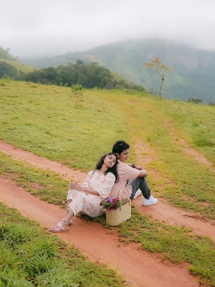A quiet moment of rest during their hilltop picnic. This shot feels intimate and peaceful, capturing the couple enjoying the scenery together.