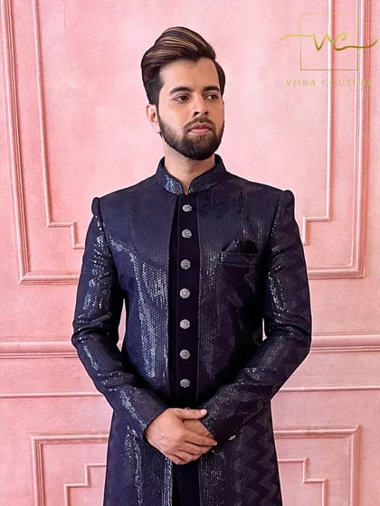 A portrait shot highlighting the fit and fabric of our custom navy blue sherwani. The silver buttons add a touch of metallic shine.