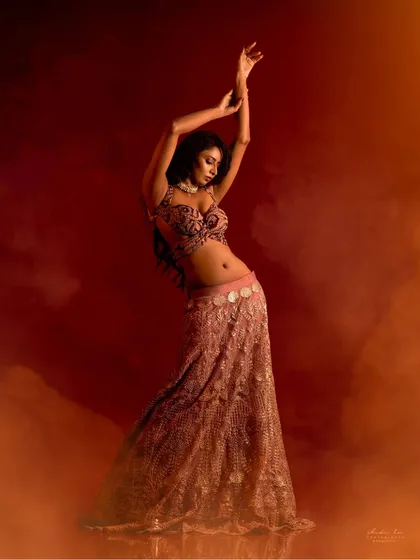 A dynamic and powerful pose in a modern lehenga. The use of smoke and dramatic backlighting creates a sense of movement and energy, perfect for a dance-themed shoot.