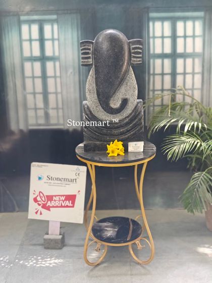 The black granite abstract Ganesha displayed on a pedestal. This view highlights its clean lines and the beautiful contrast of the carved stone.