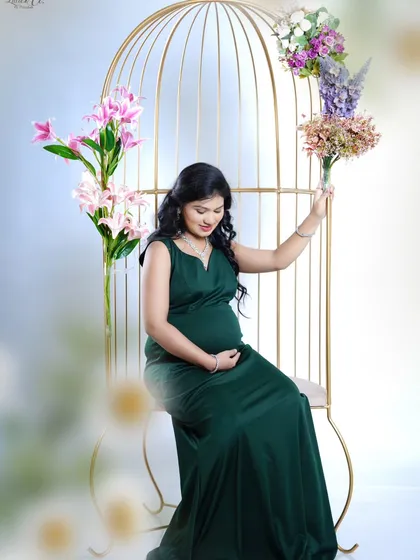 In this gentle pose, the expectant mother holds a bouquet of flowers while seated. The soft lighting and her connection with her baby bump create a peaceful and beautiful image.