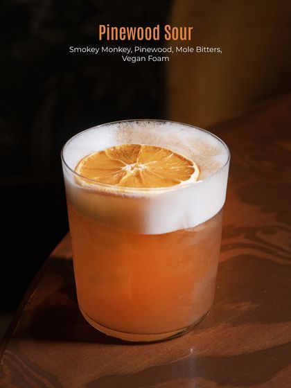 Our Pinewood Sour combines Smokey Monkey whisky with pinewood, mole bitters, and a vegan foam for a smoky, earthy, and perfectly balanced sour.