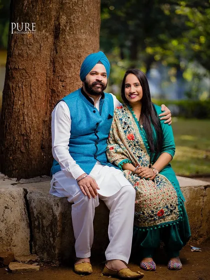 A lovely, classic portrait of Karan and Simarpreet sitting together in a park. Their traditional outfits look beautiful against the natural backdrop.