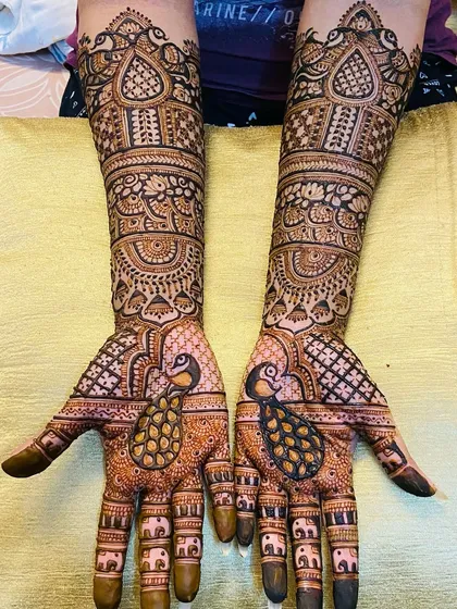 This design highlights the beauty of the peacock, with large, detailed peacock figures on the palms and smaller elephant motifs on the fingers.